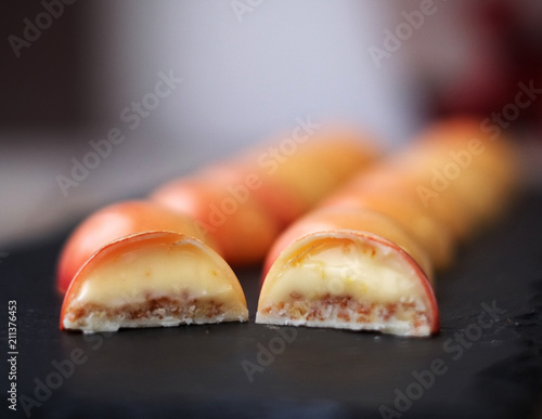 Cut of white chocolate bonbons with mango and pasiion fruit on a black board photo