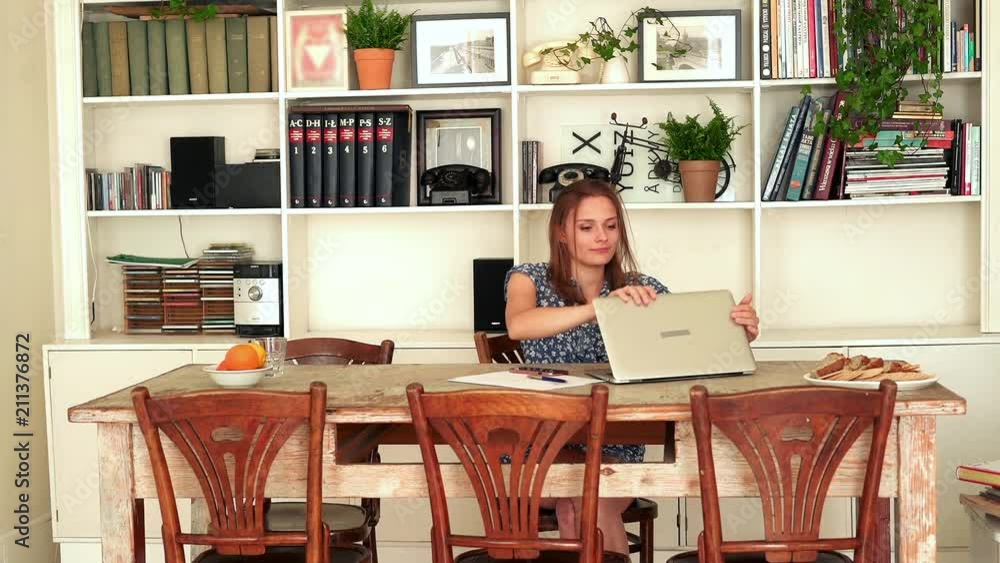 Young, pretty woman finishing working on laptop by table at home
Young, pretty woman finishing working on laptop by table at home