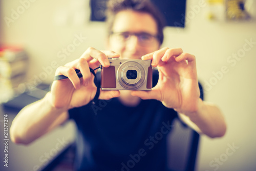 Junger Mann hält Retro-Digitalkamera in der Hand 