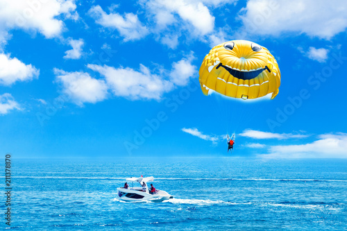 Parasailing water amusement. Flying on a parachute behind a boat on a summer holiday by the sea in the resort.  photo