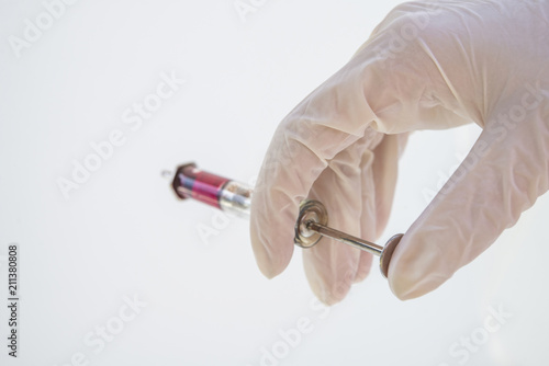 Hands with a glass syringe in gloves