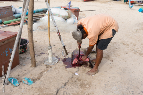 A man is cutting a shark on the beach next to the fish market in Bali