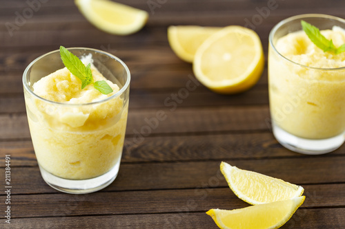 Fresh lemon citrus sorbet garnished with mint alongside.  Lemon Frozen Granita Slush Drink. 