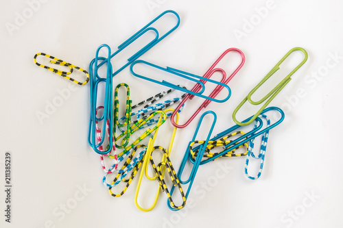 A small, multi-colored paper clip rests on white paper.