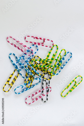A small, multi-colored paper clip rests on white paper.