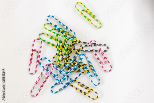 A small, multi-colored paper clip rests on white paper.