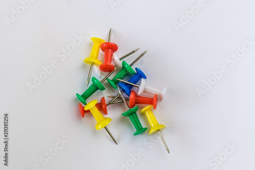 Small, colorful pins placed on white paper. Use in the office.
