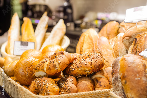 Close up freshly baked pastry goods on display in bakery shop. grocery market. Fresh bread, buns and rolls in wicker basket. Selective focus. Copy space.