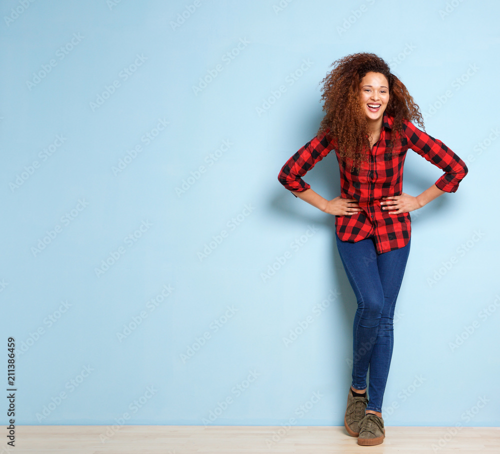 Full body young woman with curly hair laughing against blue background Full body young woman with curly hair laughing against blue background