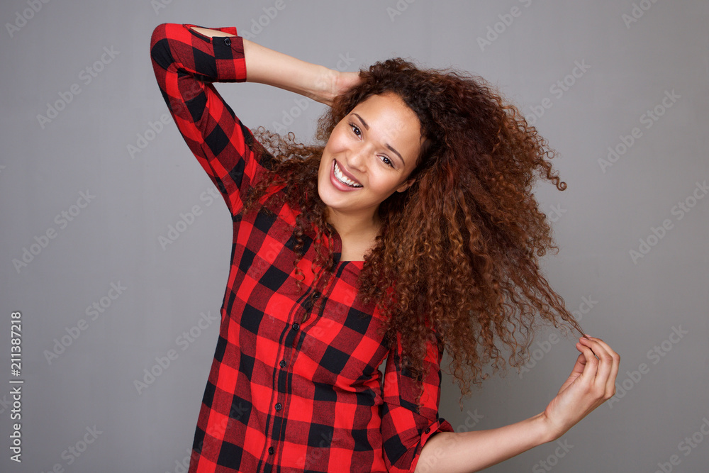 Fototapeta premium cheerful young woman smiling with hand in curly hair