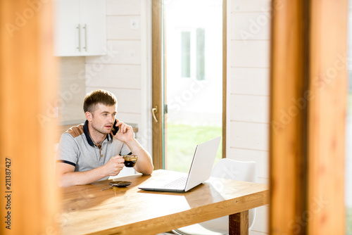Man working with laptop sitting during a breakfast with coffee at the dining room of the modern apartment