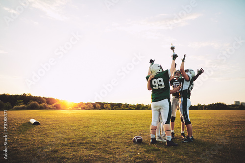 Football team celebrating with their championship trophy on a fi