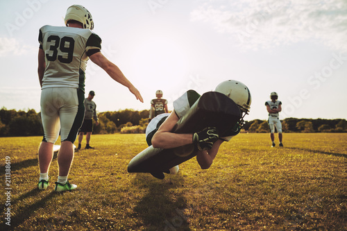 American football players practicing tackles on a football field