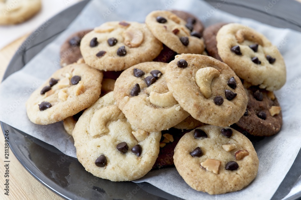 groups of Delicious Chocolate Chip Cookies on black plate, Tasty Homemade cookies on wooden table, close up dessert groups of Delicious Chocolate Chip Cookies on black plate, Tasty Homemade cookies on wooden table, close up dessert