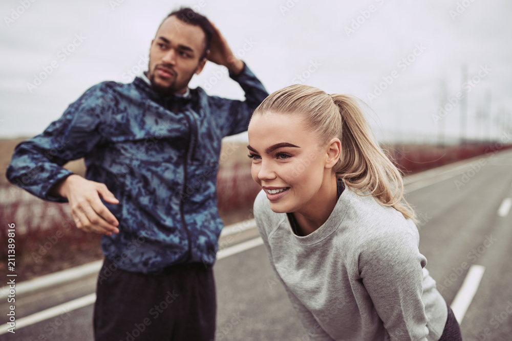 Smiling young couple preparing for an outdoor run together Smiling young couple preparing for an outdoor run together