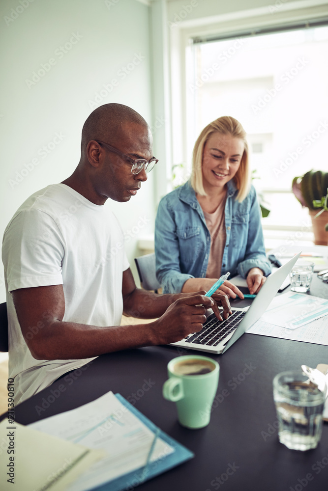 Diverse businesspeople working online with a laptop in an office Diverse businesspeople working online with a laptop in an office