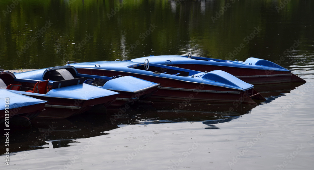 Obraz premium old and vintage blue pedal boats on a lake in bavaria, nostalgic pedal boats for rental and bathing