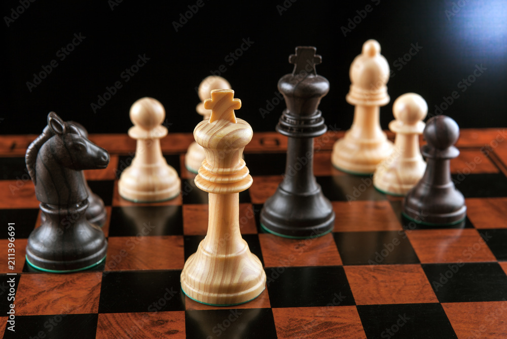 Chess pieces on a chessboard table and a chess piece of the king on a black background