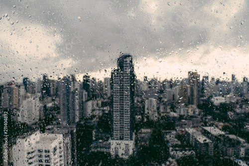 Фототапет Rain over Bangkok: Out of focus cityscape behind the window glass with rain drops
