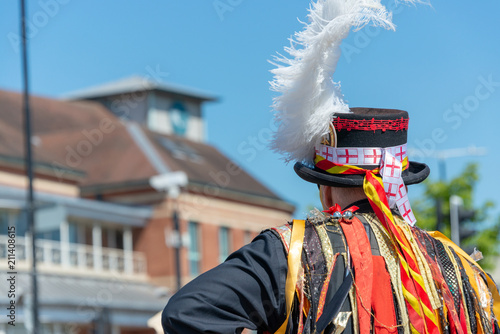 morris dancer with white feather plume in a top hat with England flags attached