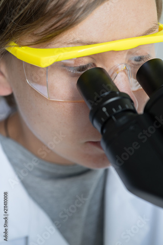 Young female scientist looking through a microscope in the laboratory.
