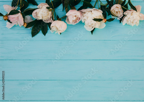 Flowers composition. Frame made of pink rose flowers on blue wooden background. Flat lay, top view, copy space.