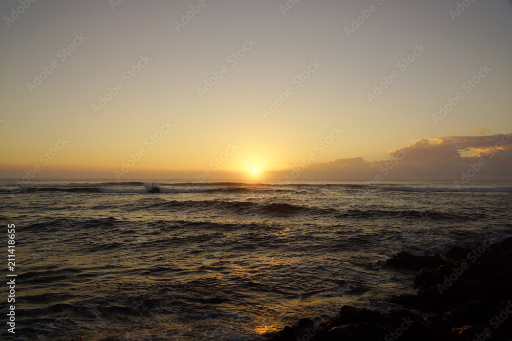 Sunrise over the ocean with waves crashing along shore