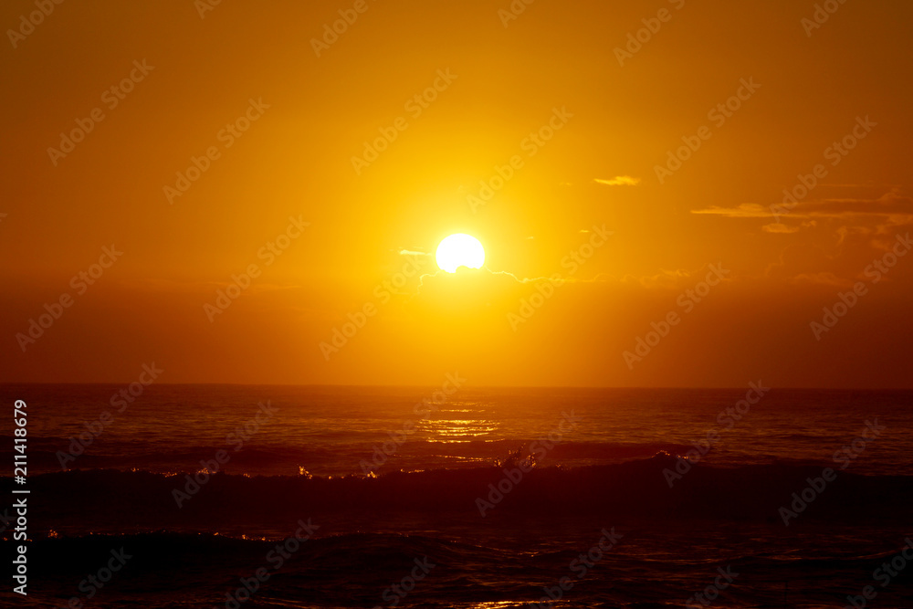 Sunrise over the ocean with waves crashing along shore Sunrise over the ocean with waves crashing along shore