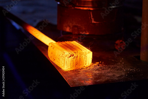 Glowing iron ingot on the table. Hot metal workpiece for the manufacture of Damascus steel.