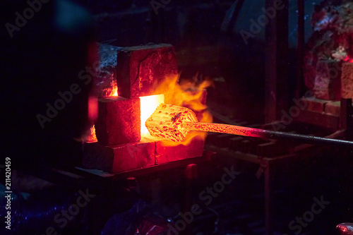 Hot item is inserted into the blacksmith's forge from which the tongues of flame. Concept: blacksmithing, forge