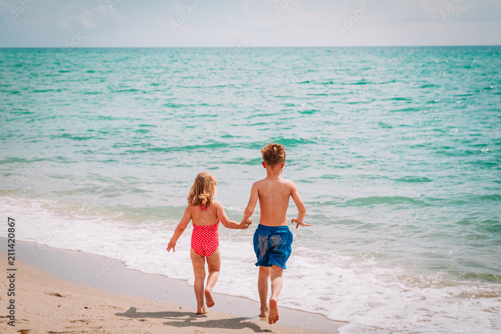 Naklejka premium little boy and girl run play at beach