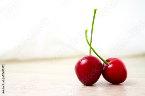 two Cherries Close-up. Cherry on wood and white background. Copyspace - healthy eating and food concept photo