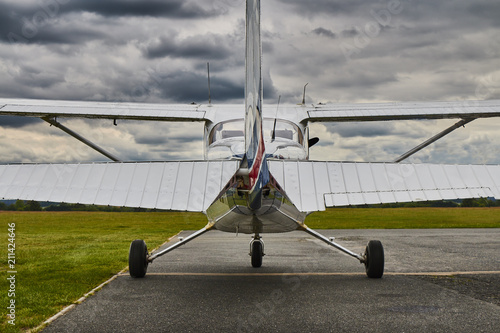 Symmetrical rear view of Cessna 172 Skyhawk 2 airplane on a runway with dramatic sky background. photo