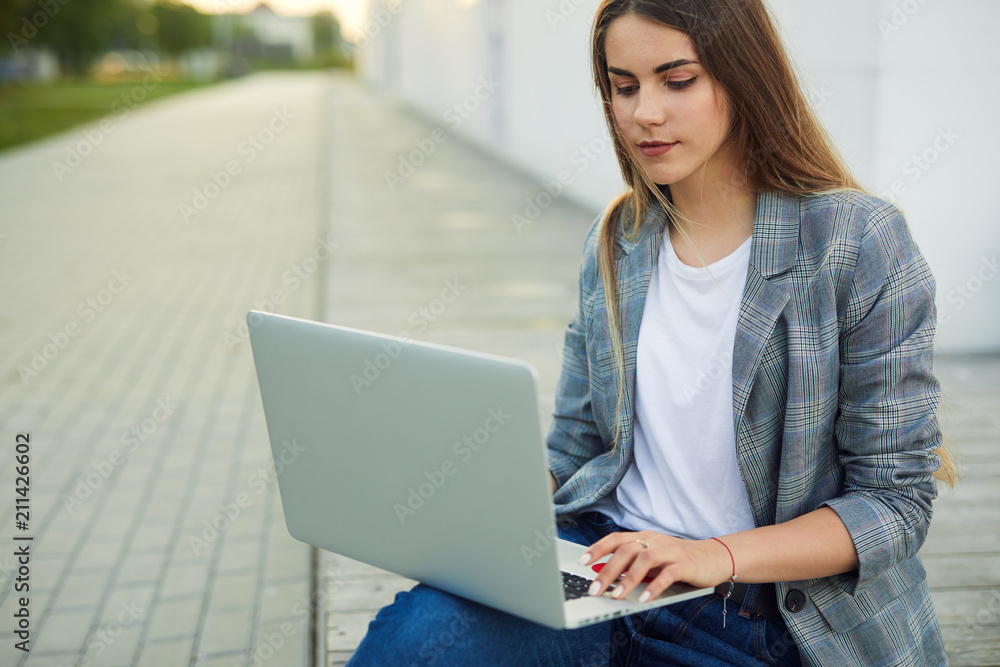 Pretty girl sit with her laptop on the city street Pretty girl sit with her laptop on the city street