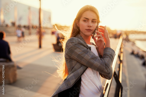 Pretty girl talk on her phone with sunset background