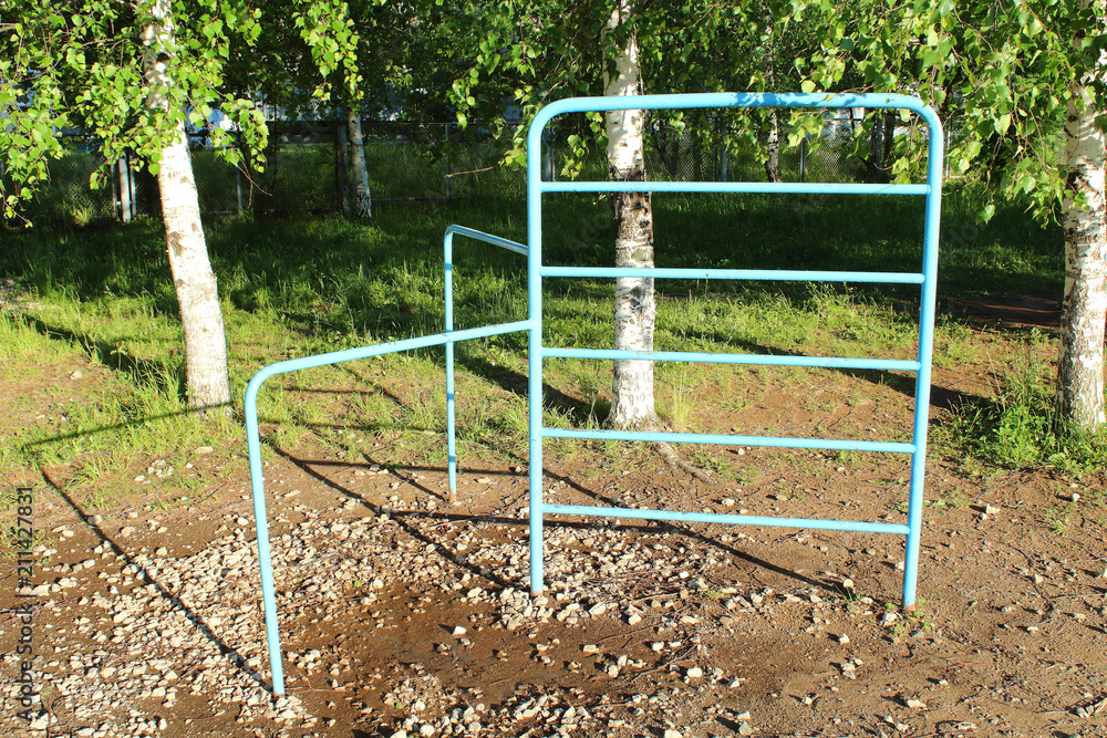 Old blue metal bar for sports. Old horizontal bar on the school grounds. Close-up. Old blue metal bar for sports. Old horizontal bar on the school grounds. Close-up.