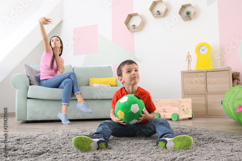 Photography Little boy playing with ball at home while his nanny is taking selfie