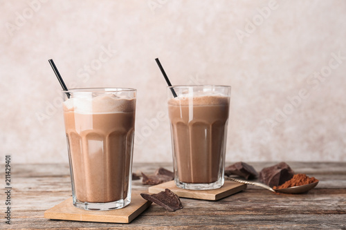 Glasses with chocolate milk shakes on wooden table