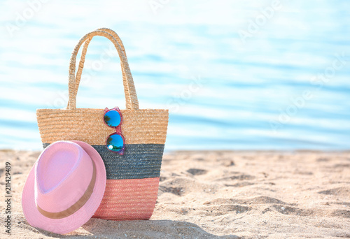 Bag, sunglasses and hat on sand near sea. Beach object
