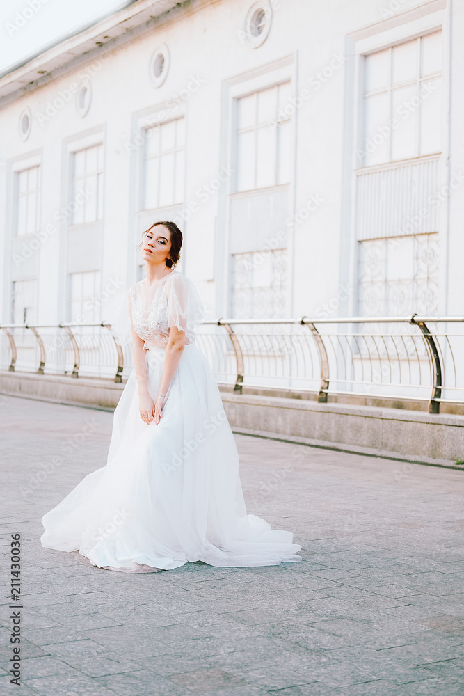 Happy young bride in flowing white dress enjoying herself outdoors