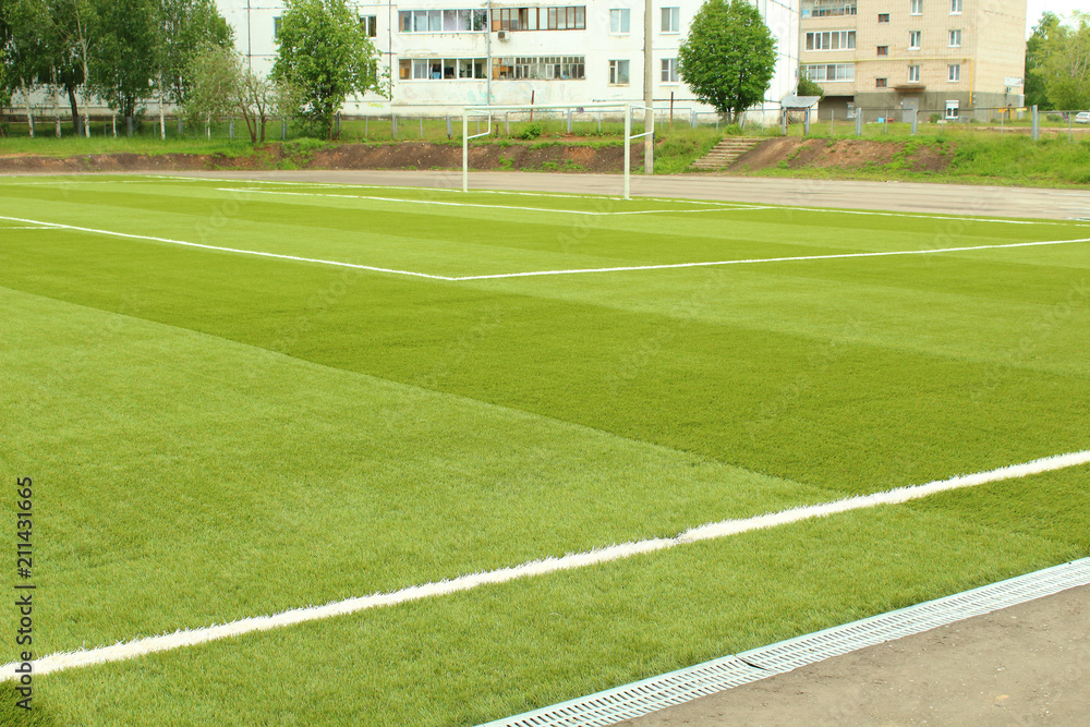 Fototapeta premium Artificial turf on the football field. Soccer field at the school stadium in the city. Background.