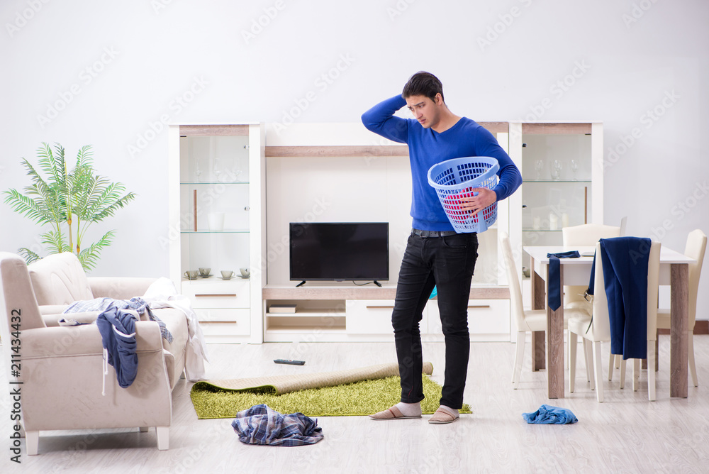 Young man collecting dirty clothing for laundry Young man collecting dirty clothing for laundry