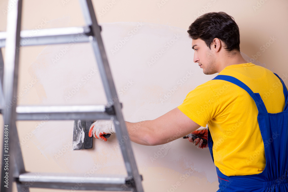 Young contractor employee applying plaster on wall Young contractor employee applying plaster on wall
