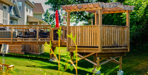Schilderij op canvas Raised backyard wooden deck and gazebo behind a row of houses