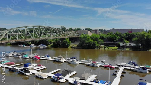 A slow forward rising aerial view of a small American town's riverfront and marina on a summer day. Business district in the distance. Pittsburgh suburbs.  	 photo