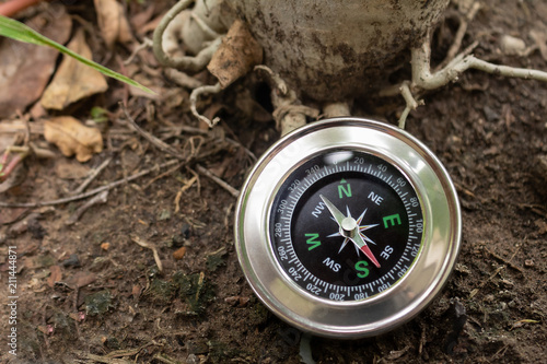 Compass on ground in forest.