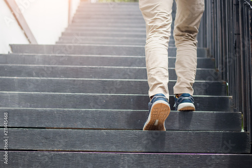 Young man walking up the stairs with sun sport background.step for success. photo