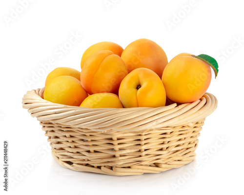 Fresh apricots in the basket are isolated on a white background.
