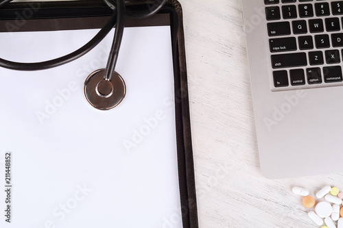 Top view of laptop, notepad and tethoscope at doctor's desk photo