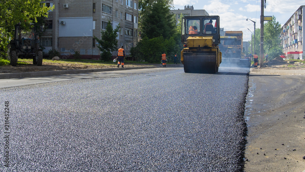 Repair works on laying the asphalt surface on a city street. Steamroller machines for laying asphalt